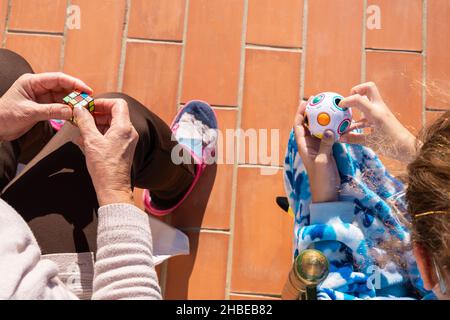 Von oben von Ernte anonyme Großmutter und Enkelin sitzen auf der Veranda an sonnigen Tag und spielen mit bunten Lernspielzeug zusammen Stockfoto
