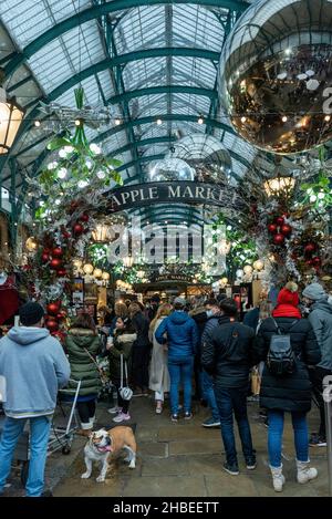 London, Großbritannien. 19. Dezember 2021. Eine Bulldogge gesellt sich am letzten Einkaufswochenende vor Weihnachten zu den Menschen unter den Dekorationen auf dem Apple Market von Covent Garden. Die Fälle der Omicron-Variante sind so stark angestiegen, dass die britische Regierung mit der Umsetzung strengerer Plan-C-Beschränkungen konfrontiert ist, um ihre Ausbreitung einzudämmen, wie zum Beispiel einem Verbot der Vermischung in Innenräumen zwischen Haushalten und einem Verbot der Innenbewirtung. Kredit: Stephen Chung / Alamy Live Nachrichten Stockfoto