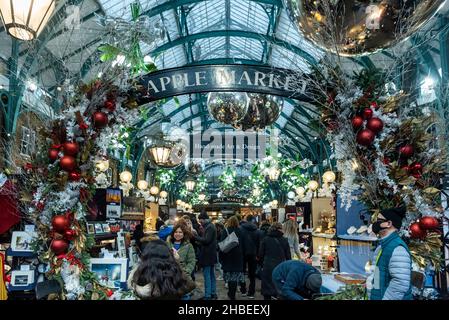 London, Großbritannien. 19. Dezember 2021. Am letzten Einkaufswochenende vor Weihnachten stehen die Menschen auf dem Apple Market von Covent Garden unter den Dekorationen. Die Fälle der Omicron-Variante sind so stark angestiegen, dass die britische Regierung mit der Umsetzung strengerer Plan-C-Beschränkungen konfrontiert ist, um ihre Ausbreitung einzudämmen, wie zum Beispiel einem Verbot der Vermischung in Innenräumen zwischen Haushalten und einem Verbot der Innenbewirtung. Kredit: Stephen Chung / Alamy Live Nachrichten Stockfoto