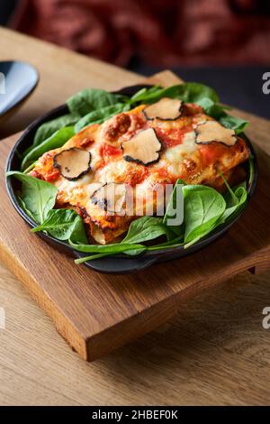 Nahaufnahme eines köstlichen Gourmet-Stücks Lasagne Bolognese auf einem Holzbrett, serviert in einem Restaurant, Menükonzept. Stockfoto