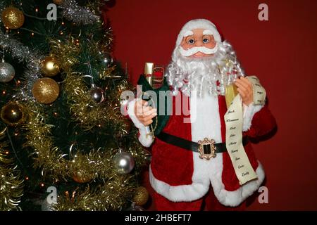 Weihnachtsmann mit einem weißen langen Bart, rotem Hut, Brille und einer grünen Tasche voller Geschenke, Weihnachtsmann und Weihnachtsbaum mit Dekoration, Weihnachtsmann Kind Stockfoto