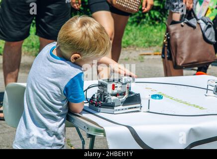 Zaporizhia, Ukraine- 19. Juni 2021: Charity Family Festival: Boy exploring robots at Outdoor modern Technologies Exhibition. Stockfoto