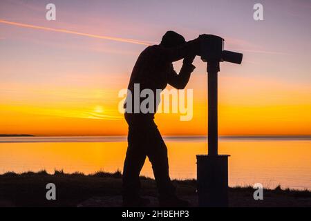 Bei,Sonnenuntergang,Silhouette,von,a,Mann,Blick,durch,Öffentlichkeit,Teleskop,Fernglas,auf,Hügel,oben,Borth,Dorf,A,Küste,Küste,Resort,auf,Cardigan Bay,Ceredigion,County,A,wenige,Meilen,Norden,von,Aberystwyth,Mid,West,Wales,Walisisch,Vereinigtes Königreich,Vereinigtes,Königreich,Großbritannien,Seeseite,Großbritannien,Britisch,landschaftlich,Aussicht,Landschaft,Landschaft Stockfoto