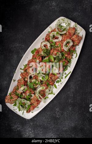 LULYA-KEBAB mit Kräutern und Zwiebeln auf einem Teller Stockfoto