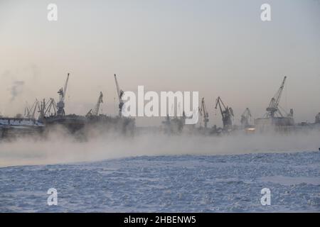 Der Bau von nuklearen Eisbrechern, Kräne der baltischen Werft in einem frostigen Wintertag, Dampf über dem Fluss Neva, glatte Oberfläche der Stockfoto