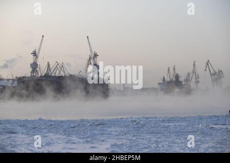 Der Bau von nuklearen Eisbrechern, Kräne der baltischen Werft in einem frostigen Wintertag, Dampf über dem Fluss Neva, glatte Oberfläche der Stockfoto