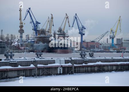 Der Bau von nuklearen Eisbrechern, Kräne der baltischen Werft in einem frostigen Wintertag, Dampf über dem Fluss Neva, glatte Oberfläche der Stockfoto