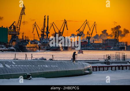 Der Bau von nuklearen Eisbrechern bei magischem Sonnenuntergang, Kräne der baltischen Werft in einem frostigen Wintertag, Dampf über dem Fluss Neva, glatt Stockfoto