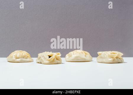 Manty mit Fleisch, Tomaten, Kräutern, Sauce und Pfeffererbsen auf grau minimalistisch Stockfoto