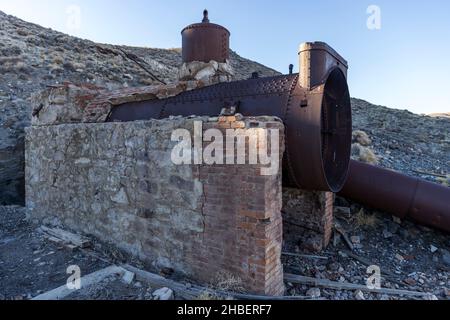 Der alte Bergbauofen ist teilweise noch mit einer Ziegelstruktur bedeckt, wobei die Rohre in der Wüste auf dem Boden liegen Stockfoto