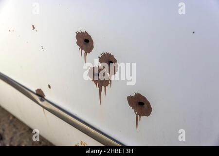 Rostige Einschusslöcher an der Seite einer alten Autotür Stockfoto