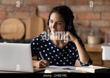 Glückliche interessierte junge hispanische Frau, die entfernt studiert. Stockfoto