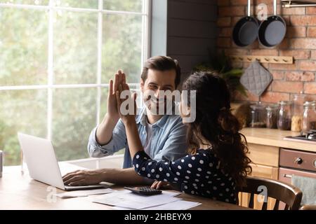 Glückliches junges Familienpaar feiert erfolgreiche Investition. Stockfoto