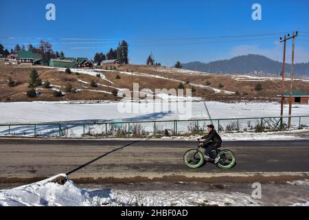 Gulmarg, Indien. 19th Dez 2021. Ein Radfahrer fährt an einem kalten Wintertag in einem berühmten Skigebiet in Gulmarg, etwa 55kms von Srinagar entfernt, entlang einer Straße. Kredit: SOPA Images Limited/Alamy Live Nachrichten Stockfoto