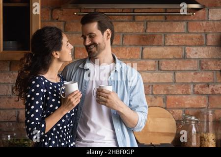 Glückliches junges Familienpaar trinkt Kaffee in der Küche. Stockfoto