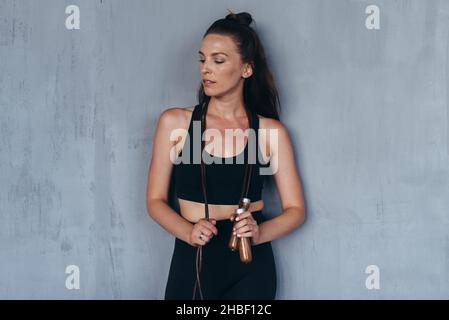 Porträt eines sportlichen Mädchens mit einem Springseil, das gegen die Wand steht. Stockfoto