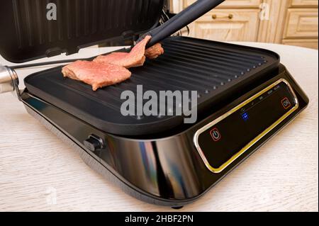 Nahaufnahme roher Fleischstücke aus Schweinefleisch auf elektrischem Grill Stockfoto