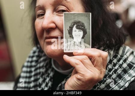 Ältere Frau mit einem schwarz-weißen Foto ihres jungen selbst. Konzept des Zeitvergehens Stockfoto