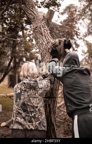 Zwei Männer schneiden einen Baum ab. Die Gegend von alten Bäumen entfernen. Stockfoto