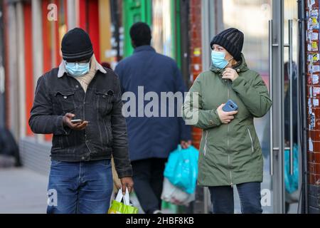 London, Großbritannien. 10th Dez 2021. Menschen, die Gesichtsmasken tragen, benutzen ihre Handys, während sie auf der Straße gehen. Kredit: SOPA Images Limited/Alamy Live Nachrichten Stockfoto