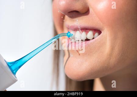 Nahaufnahme einer Frau mit perfektem Lächeln mit Wasserfoser oder Munddusche Stockfoto