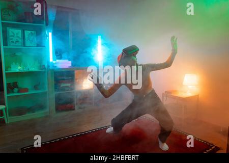 Wireless-Technologien. Junge Frau mit Virtual-Reality-Brille im dunklen Raum mit Neonbeleuchtung. Stockfoto