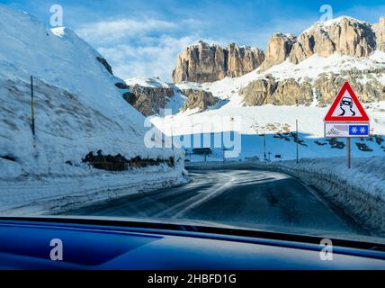 Gefahr des Schleuderens in Kurven auf einer verregneten oder vereisten Straße in den Bergen. Vereiste kurvige Straße mit Verkehrszeichen. Stockfoto