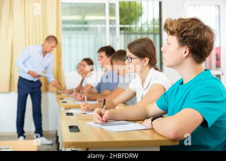 Jugendliche hören dem Dozenten zu und schreiben in Notizbüchern Stockfoto