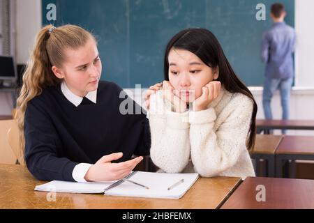 Teen weibliche Student Unterstützung verärgert chinesisches Mädchen im Klassenzimmer Stockfoto