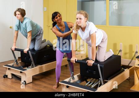 Kleiner Junge und Mädchen mit Pilates-Trainer im Fitnessstudio Stockfoto