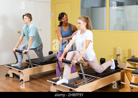 Kleiner Junge und Mädchen mit Pilates-Trainer im Fitnessstudio Stockfoto