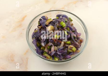 Gekochter Rotkohl in Scheiben und grüne Zwiebeln in einer Schüssel mit Glaszutaten, die zum Gericht hinzugefügt werden kann Stockfoto
