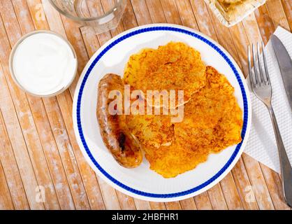 Kartoffelpfannkuchen mit Wurst und Sauerrahm Stockfoto