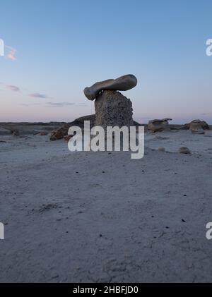 Erodierter Steinsockel mit Kappe in Bisti Badlands oder De-Na-Zin Wilderness in New Mexico in der Abenddämmerung. Stockfoto