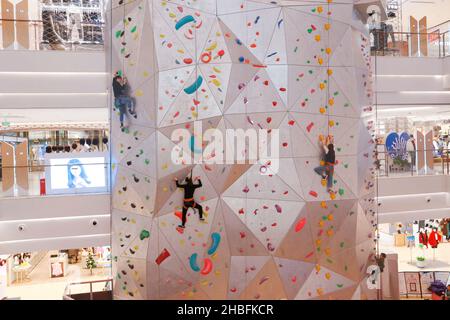 SHANGHAI, CHINA - 19. DEZEMBER 2021 - Winter-Fitness-Enthusiasten erleben die höchste Indoor-Kletterwand der Welt in der New World Mall, a com Stockfoto