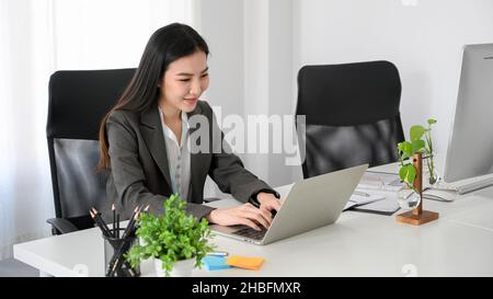 Schöne asiatische junge Geschäftsfrau oder Marketing-Arbeiter arbeitet auf Laptop-Computer im Büro-Arbeitsplatz. Stockfoto