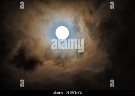 Ein Vollmond, der durch die Wolken blickt. Stockfoto