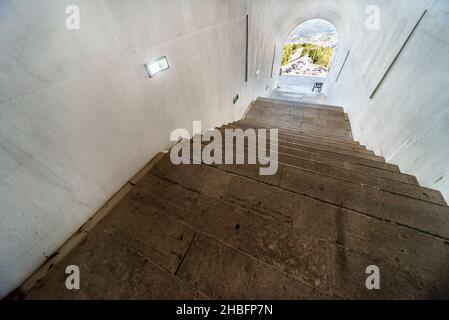 Lovcen Nationalpark. Schwach beleuchtete steile, weiße Steintreppen, die durch einen langen schmalen Tunnel im Berg hinauf zum Mausoleum von Petar II Petrovic führen. Stockfoto