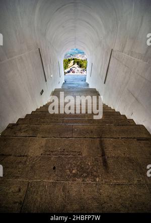 Lovcen Nationalpark. Schwach beleuchtete steile, weiße Steintreppen, die durch einen langen schmalen Tunnel im Berg hinauf zum Mausoleum von Petar II Petrovic führen. Stockfoto