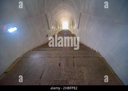 Lovcen Nationalpark. Schwach beleuchtete steile, weiße Steintreppen, die durch einen langen schmalen Tunnel im Berg hinauf zum Mausoleum von Petar II Petrovic führen. Stockfoto