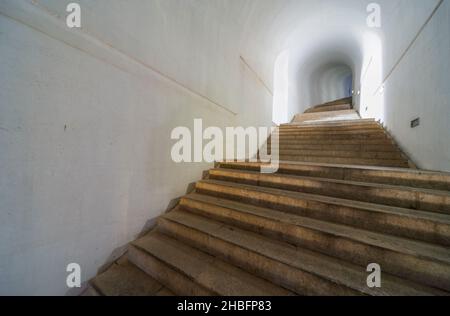 Lovcen Nationalpark. Schwach beleuchtete steile, weiße Steintreppen, die durch einen langen schmalen Tunnel im Berg hinauf zum Mausoleum von Petar II Petrovic führen. Stockfoto