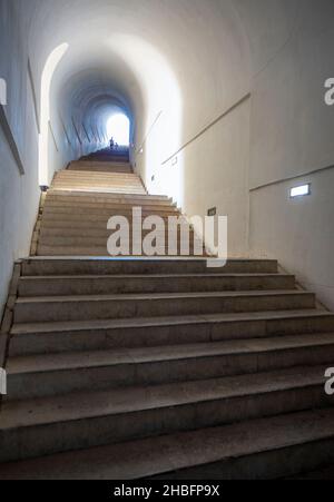 Lovcen Nationalpark. Schwach beleuchtete steile, weiße Steintreppen, die durch einen langen schmalen Tunnel im Berg hinauf zum Mausoleum von Petar II Petrovic führen. Stockfoto