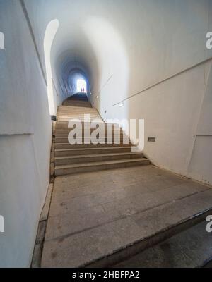 Lovcen Nationalpark. Schwach beleuchtete steile, weiße Steintreppen, die durch einen langen schmalen Tunnel im Berg hinauf zum Mausoleum von Petar II Petrovic führen. Stockfoto