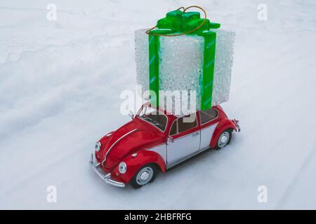 Kleines rotes Retro-Auto, das ein weihnachtsgeschenk ausliefert Stockfoto