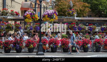 Leute, die auf der Terrasse des Straßenrestaurants sitzen. Fröhliche Leute essen gemeinsam lokale Gerichte im Open Air Restaurant. Stockfoto