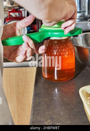 Der Küchenchef öffnet ein Glas Honig mit einem speziellen Schlüssel Stockfoto