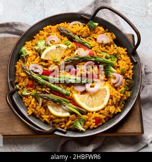 Vegane Paella auf grauem Hintergrund. Mediterrane Ernährung. Gesundes Lebensmittelkonzept. Flach liegend, Draufsicht Stockfoto