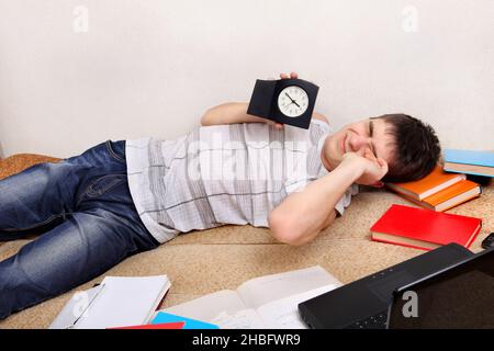 Müder Teenager auf dem Sofa mit der Uhr Stockfoto