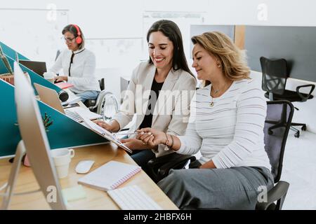Zwei lateinische Geschäftsfrau im mittleren Alter, die sich im Büro in Mexiko, Lateinamerika, unterhalten und beraten Stockfoto
