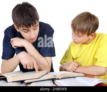 Der ältere Bruder hilft dem kleinen Bruder bei einer Hausaufgabe auf dem weißen Hintergrund Stockfoto